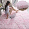A young woman relaxing on a pink plush area rug with a laptop, next to a close-up of the fluffy pink rug.