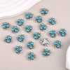 A set of flower-shaped resin button rhinestones in blue and silver tones scattered on a light background.