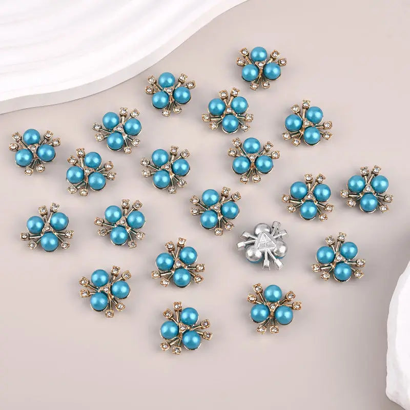 A set of flower-shaped resin button rhinestones in blue and silver tones scattered on a light background.