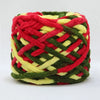 A ball of red, green, and yellow chenille knitting yarn with a woven texture.