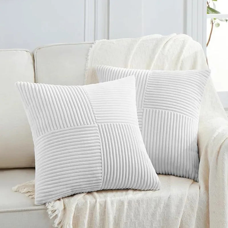 A close-up of white retro corduroy patchwork pillow covers resting on a light-colored sofa.