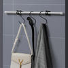 Silver curtain rod clips mounted on a gray tiled wall, with a black garment hanging from one clip.