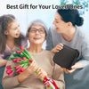 Three women smiling while one gives a gift of tulips to another
