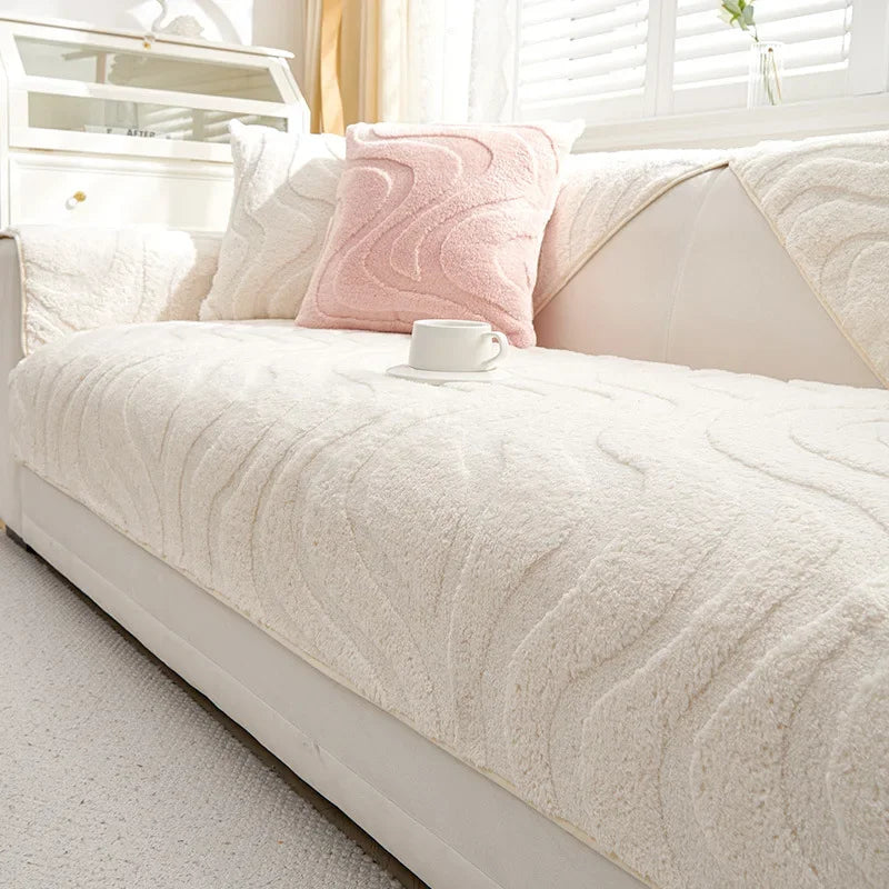 A cream colored sofa cushion cover with a textured, wavy pattern and a pink accent pillow on a white bed.