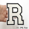 A hand holds a white letter R patch with black outline and stitching on a white background.