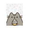 A cute gray cat face with a swirl of cream on its head is featured on a white blanket sprinkled with colorful confetti.