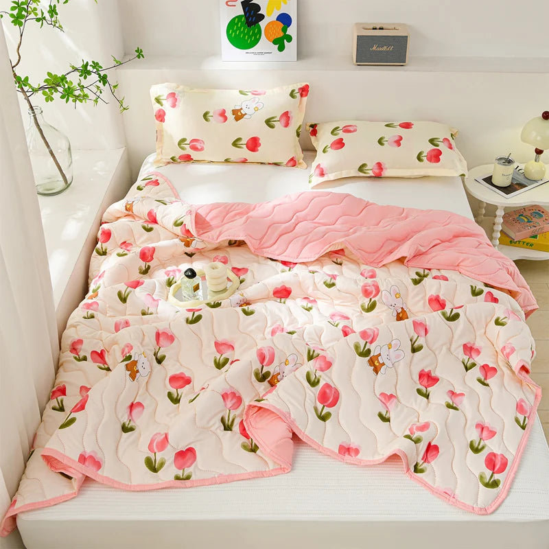 A pink and white quilted summer quilt set with floral patterns displayed on a bed.