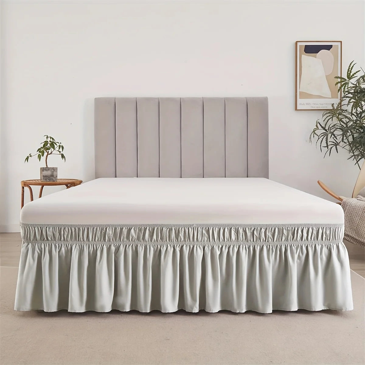 A light beige adjustable elastic bed skirt with a ruffled trim and upholstered headboard.