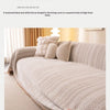 A beige chenille sofa protector draped over a light-colored sofa with a textured pattern.
