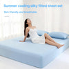 A woman is lying on a light blue bed with a white silky fitted sheet set, demonstrating the breathable fabric.