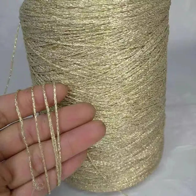 A hand holds strands of glitter metallic yarn coiled in a large skein for crochet and knitting