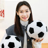 A woman holds a black and white three-dimensional football figurine plush toy.