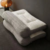 A stack of light gray and white 3D ergonomic contour pillows for neck and spine support resting on a dark carpet.