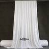 White draping stretch fabric hanging vertically against a dark background.