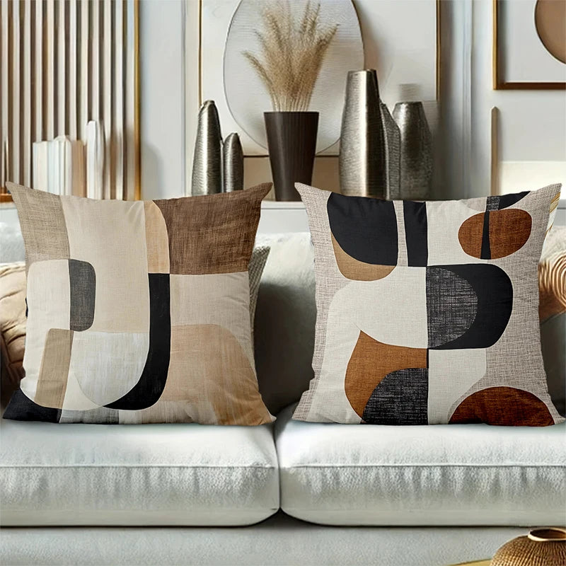 A close-up of a decorative pillow cover featuring geometric shapes in beige, black, and terracotta tones.