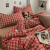 A red and green plaid duvet cover set displayed on a bed with pillows and a teddy bear.