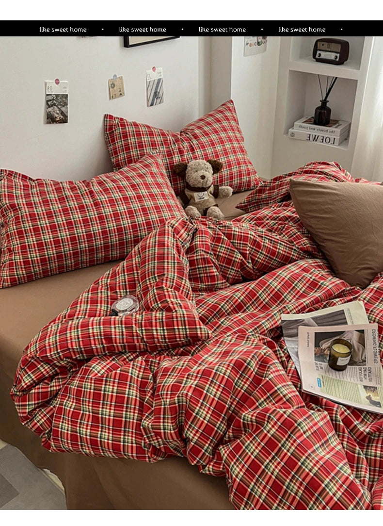 A red and green plaid duvet cover set displayed on a bed with pillows and a teddy bear.