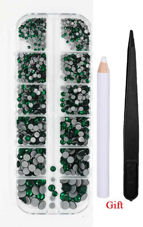 A clear plastic container holds various green and silver crystal rhinestones and an applicator tool for crafting.