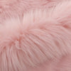 Close-up of a soft pink faux fur area rug showing its plush texture and fluffy fibers.