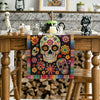 A colorful skull and floral day of the dead table runner displayed on a wooden table.