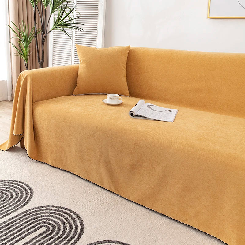A mustard yellow waterproof sofa cover blanket draped over a sofa on a light rug.