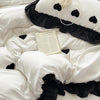 A white duvet set featuring black heart embroidery and ruffled black fabric.