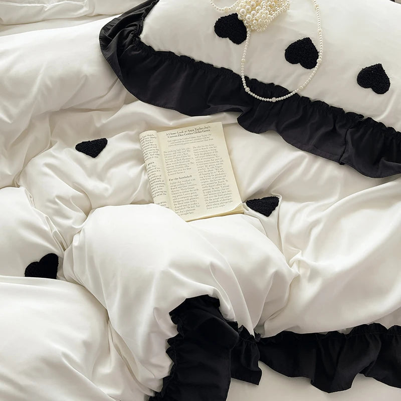 A white duvet set featuring black heart embroidery and ruffled black fabric.