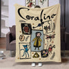 A cream colored flannel throw blanket featuring a black line drawing of the name Coraline and various whimsical illustrations