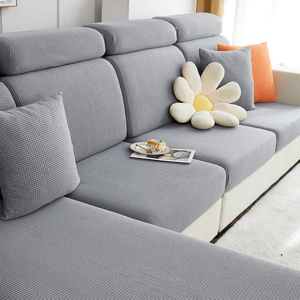 A gray sofa seat cushion cover featuring a large, cream-colored flower accent pillow.