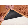 A hand is pressing a black, triangular non-slip carpet gripper onto a beige carpet surface.