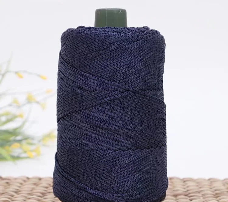 A dark navy blue crochet ice rope with a green cap, coiled on a woven mat.