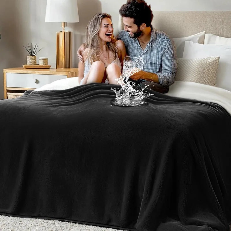 A couple laughing while playfully splashing water on a black flannel blanket in a bedroom setting.