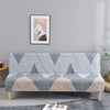 Geometric print spandex slipcovers on a sofa bed with a framed artwork hanging above.