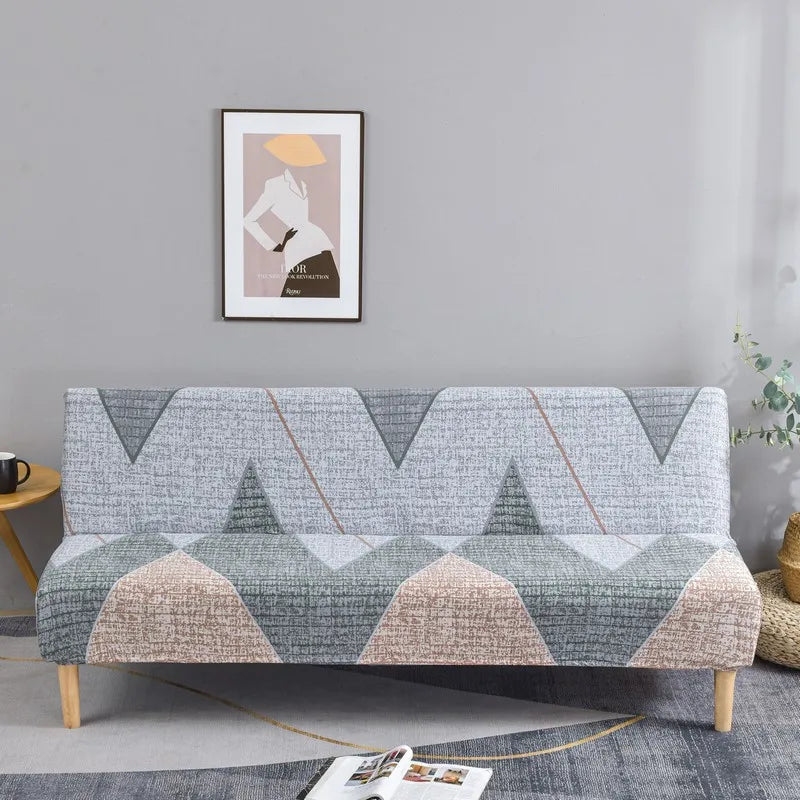 Geometric print spandex slipcovers on a sofa bed with a framed artwork hanging above.