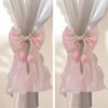 A pair of pink sheer ribbon bow curtain tiebacks displayed on a hanger.