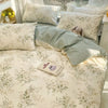 A light floral patterned bedding set featuring cream and sage green tones with fluffy pillows.
