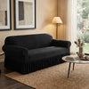 A dark gray dustproof stretch sofa slipcover placed in a living room with natural light and sheer curtains.