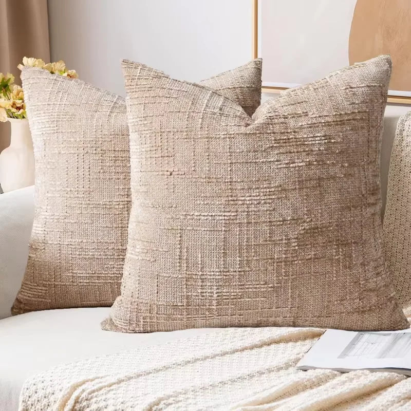 A beige boucle texture throw pillow cover resting on a white sofa with natural light.