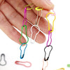 A hand holds several colorful gourd-shaped locking safety pins for knitting and sewing.
