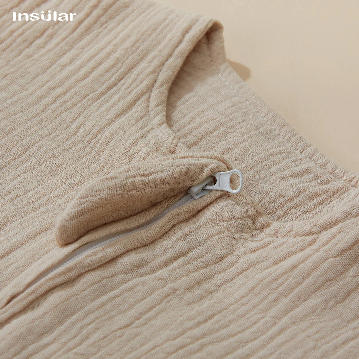 Close-up of a beige muslin cotton baby sleeping bag with a zippered pocket on the chest area.