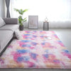 A fluffy tie-dye silk wool rug in pink, purple, and blue is displayed on a light floor.
