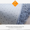 Close-up view of a gray tie-dyed plush floor mat showing the point plastic bottom texture.