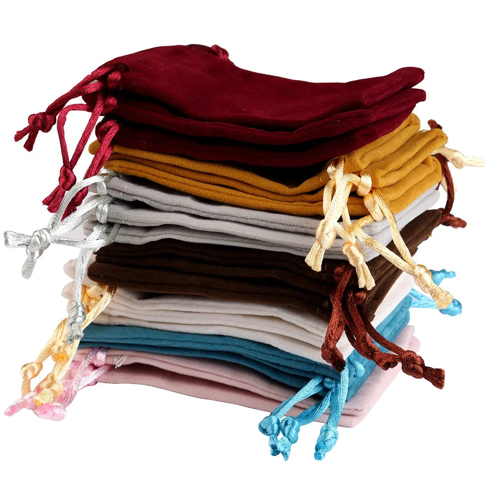 A stack of velvet drawstring jewelry gift bags in various shades including maroon, gold, gray, brown, and blue.