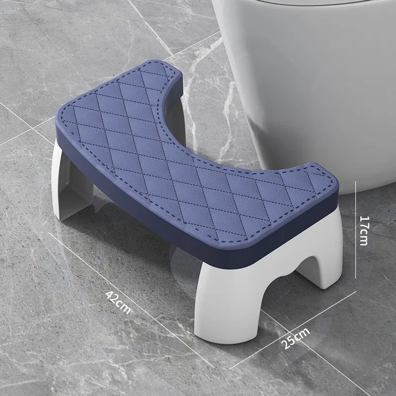 A purple quilted adult toilet squat stool with white supports shown on a gray surface.