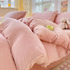 A pink velvet duvet cover set with fluffy pillows and a stuffed rabbit toy on a bed.
