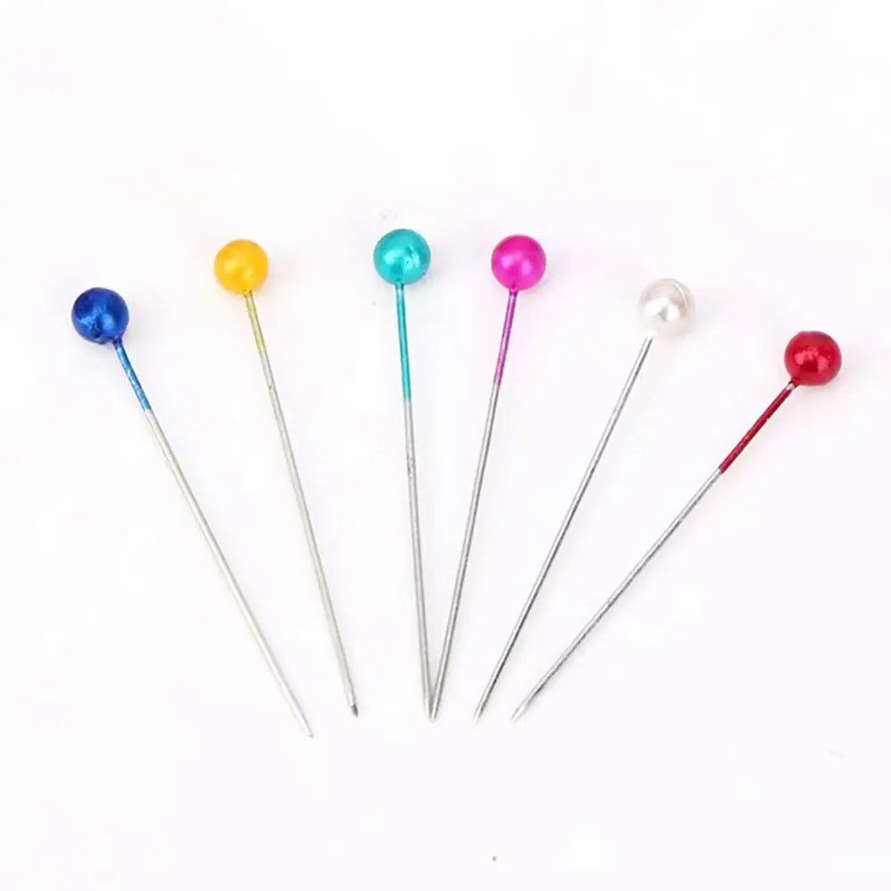 A set of colorful pearl head pins with various colored beads and silver-toned pins.