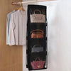 A black hanging closet organizer bag with multiple compartments displaying various handbags.