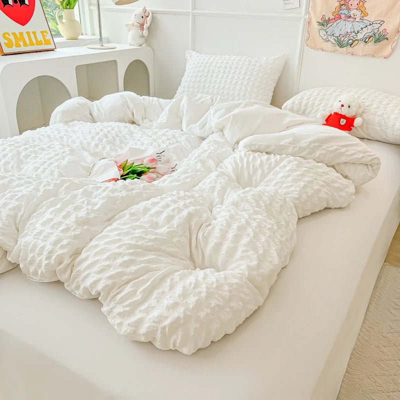 A white seersucker duvet cover and pillow set displayed on a white bed with decorative pillows.