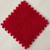 A square red plush interlocking puzzle rug mat with a textured surface.