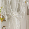 White French Rococo vintage lace curtains tied in a bow, displayed against white paneling.